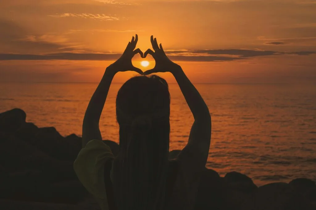 Affirmations For Heart Chakra Healing and Balancing sun framed in hand sign of heart